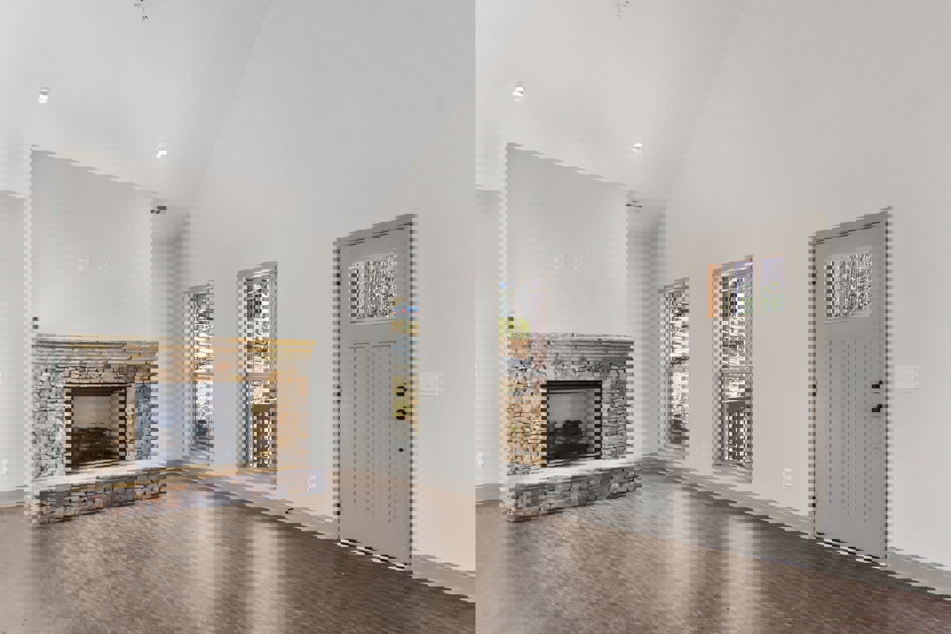 Living room with wood flooring, white trim, central fireplace with glass door, white door with window, large window overlooking trees