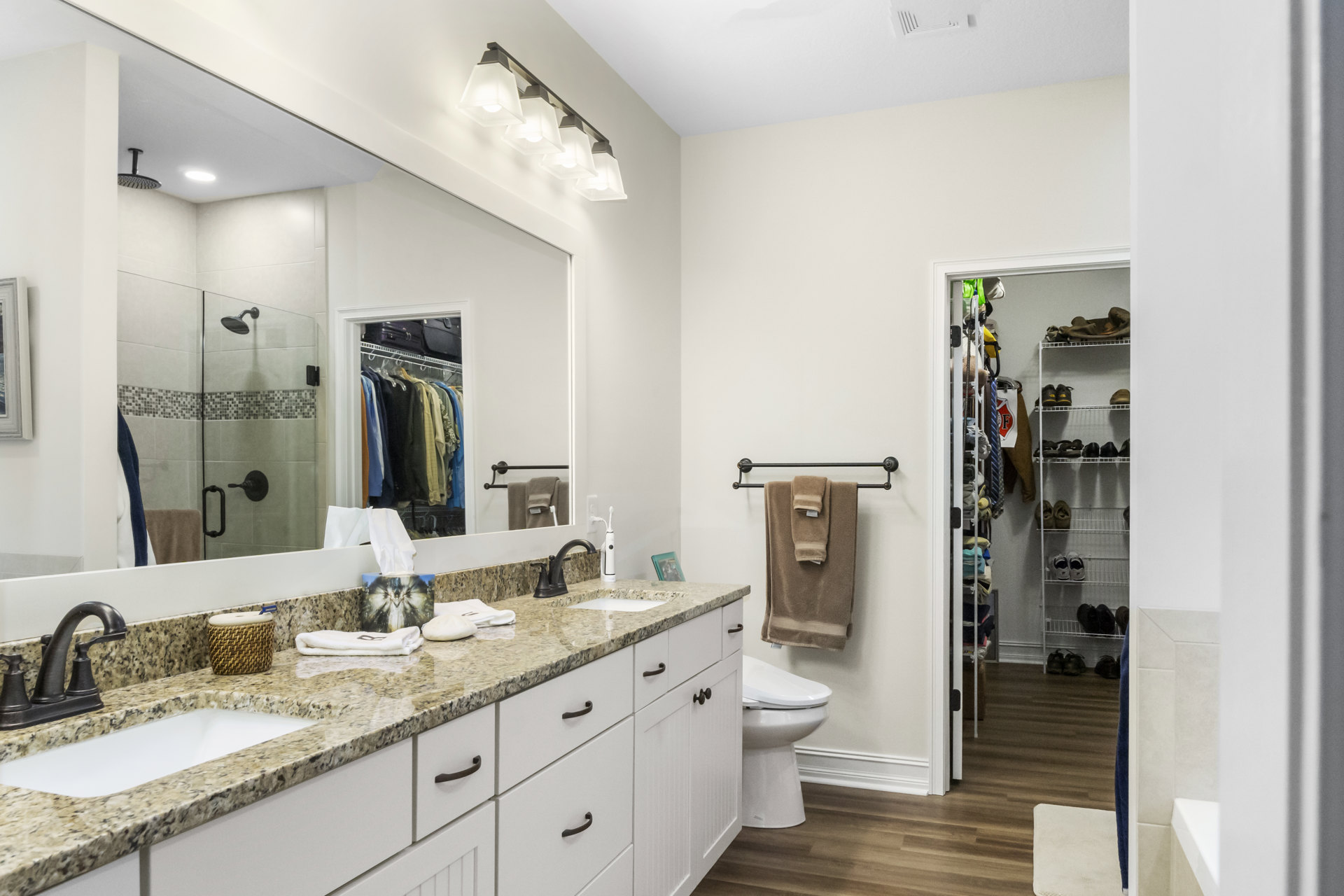 Marble countertop with black faucet, rectangular mirror above sink, brown towel hanging on wall, wicker basket holding toothbrush, tissue box with angel illustration