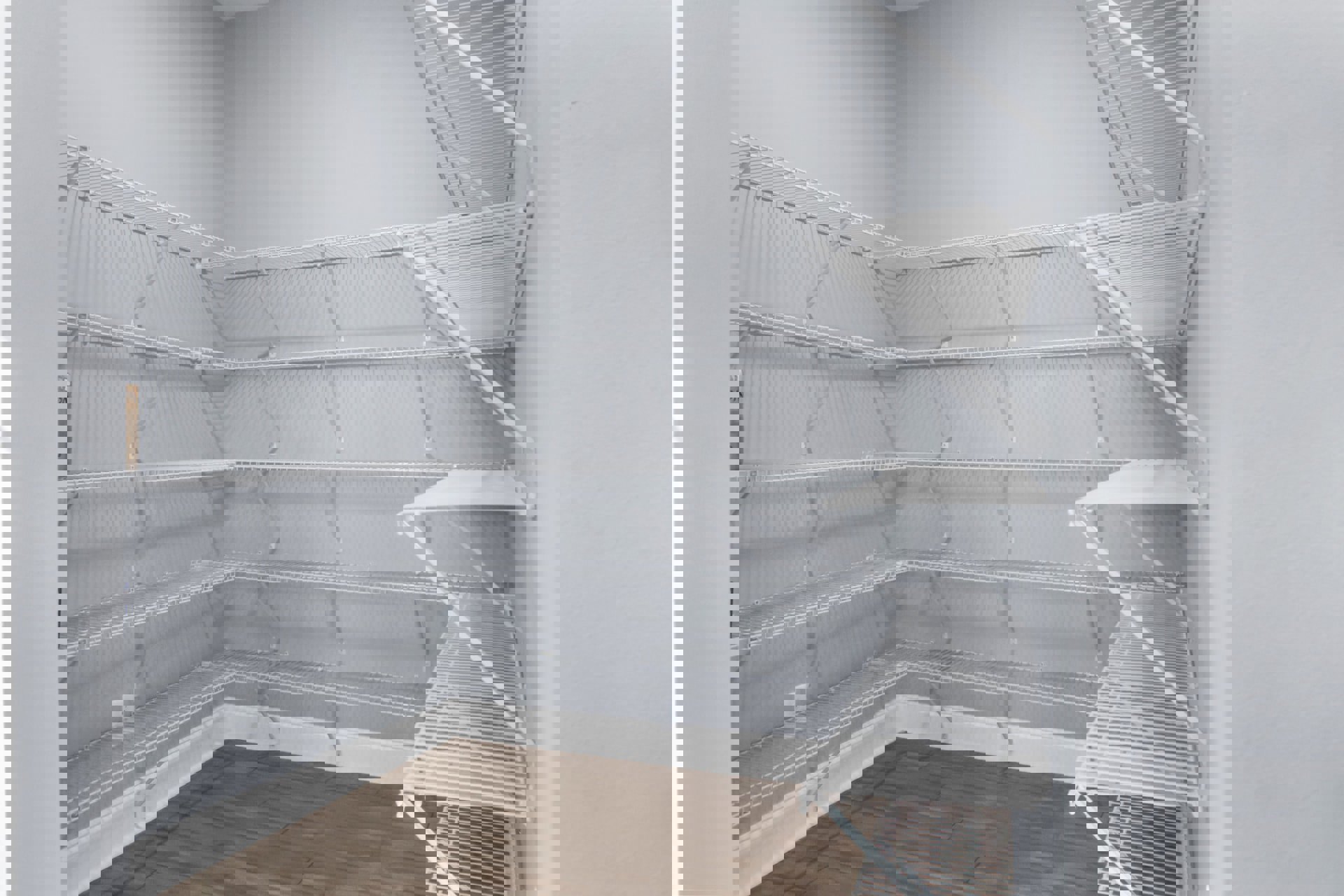 White built-in shelves along a plaster wall, wood flooring, exposed metal rods on the ceiling, open and unfurnished room.