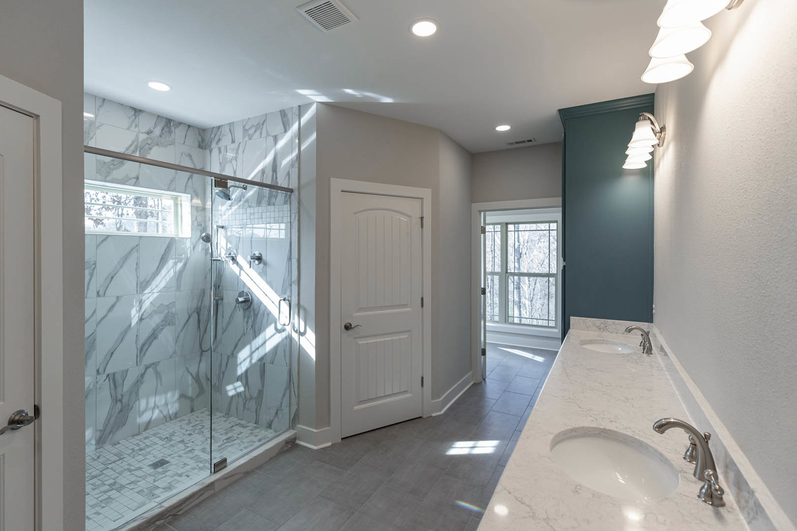 Bathroom featuring marble countertops, glass-enclosed shower, white circular sink with chrome faucet, white door, ceiling light, and tiled walls