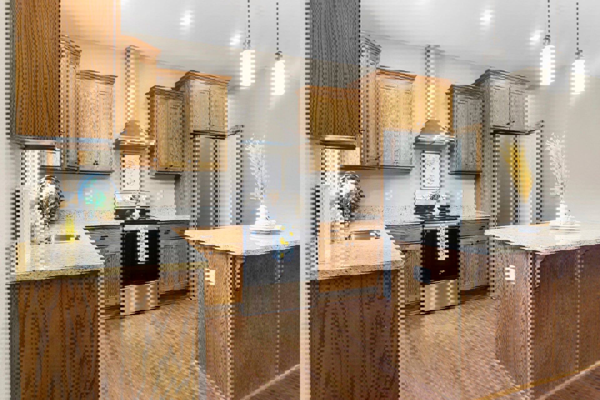 Kitchen with natural wood cabinets, speckled granite countertops, black oven topped with a white vase, tall yellow plant in a white vase, kitchen island displaying a plate of food