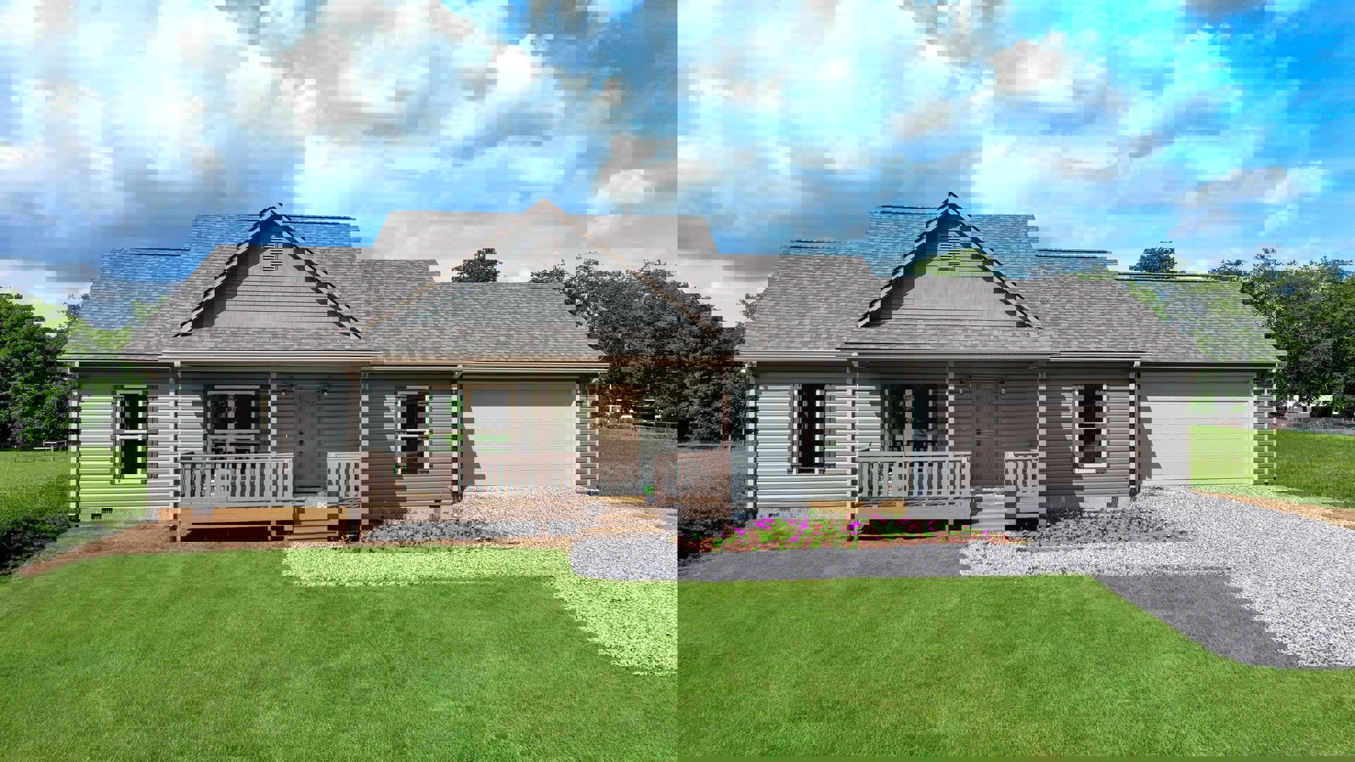White siding house with covered front porch, wooden columns, green lawn, and gabled roof with vent under partly cloudy sky