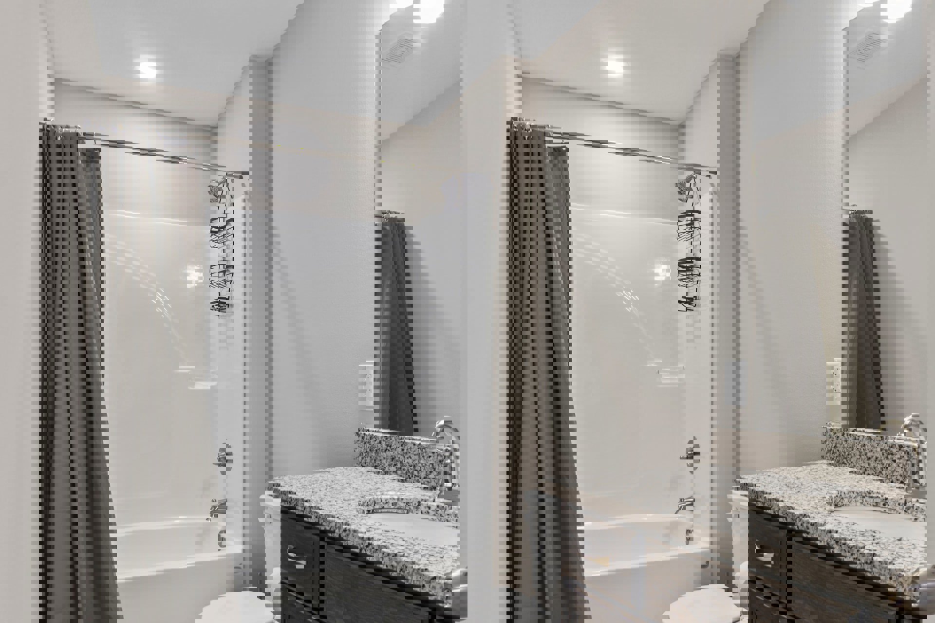 White bathroom with tiled shower, grey curtain, built-in bathtub, white countertop sink, chrome faucet, and wall outlet