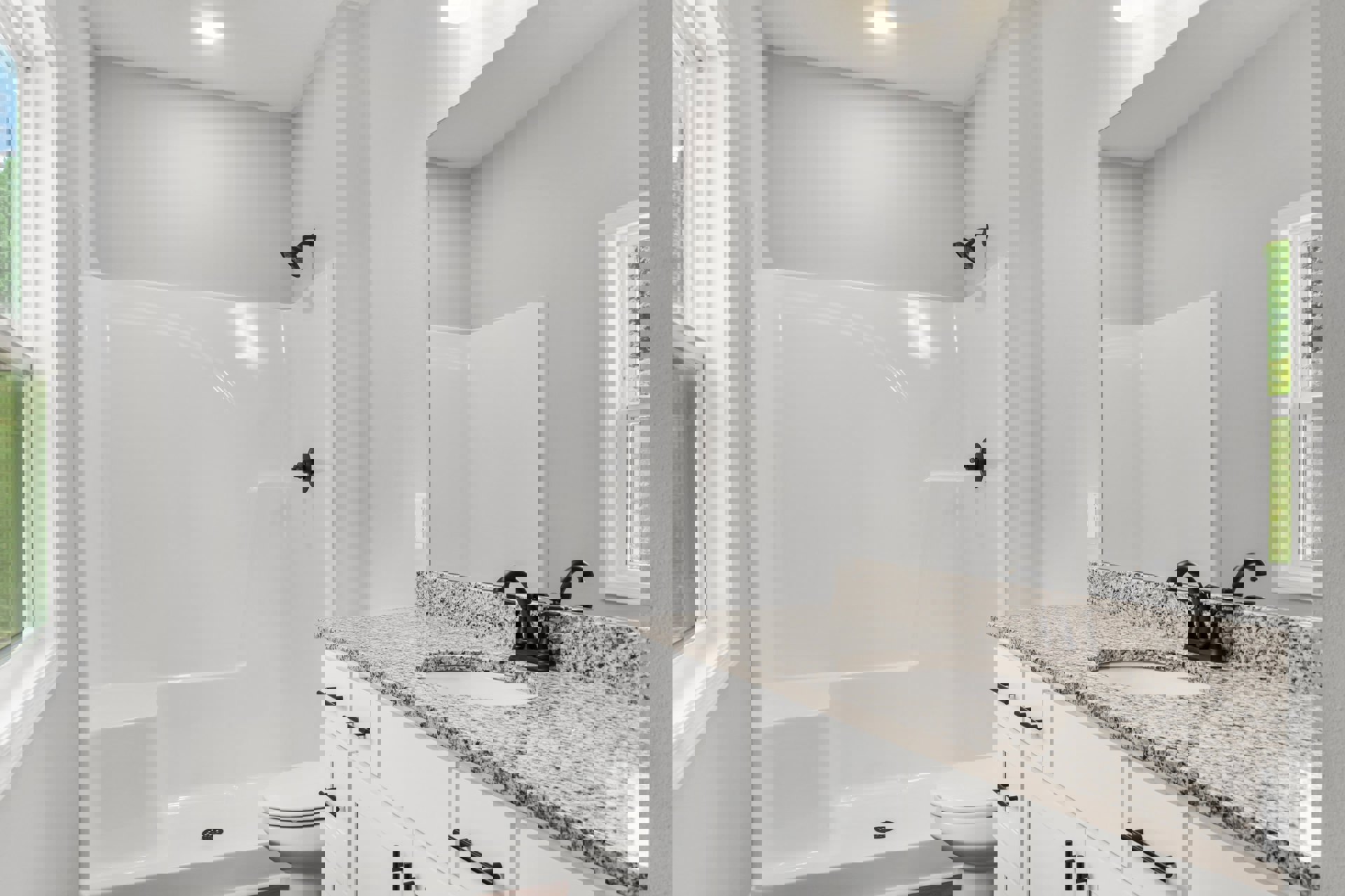 Modern bathroom featuring a white tile shower with black handle, white toilet, light stone countertop with undermount sink, chrome faucet, and a window above the vanity.