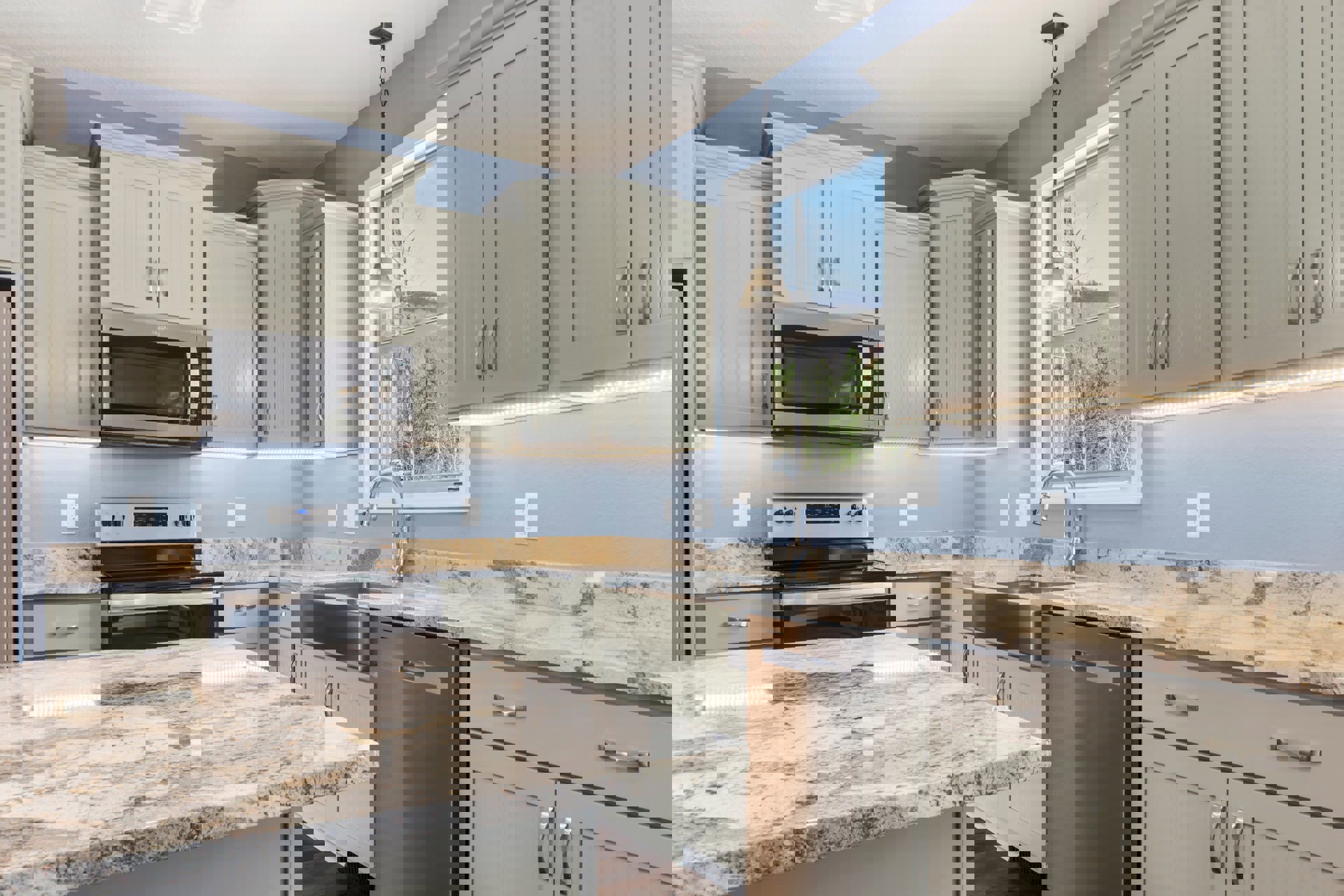 Marble countertop with black and white speckled surface, stainless steel dishwasher, built-in microwave with black screen, open oven door, silver drawer, white door with vertical