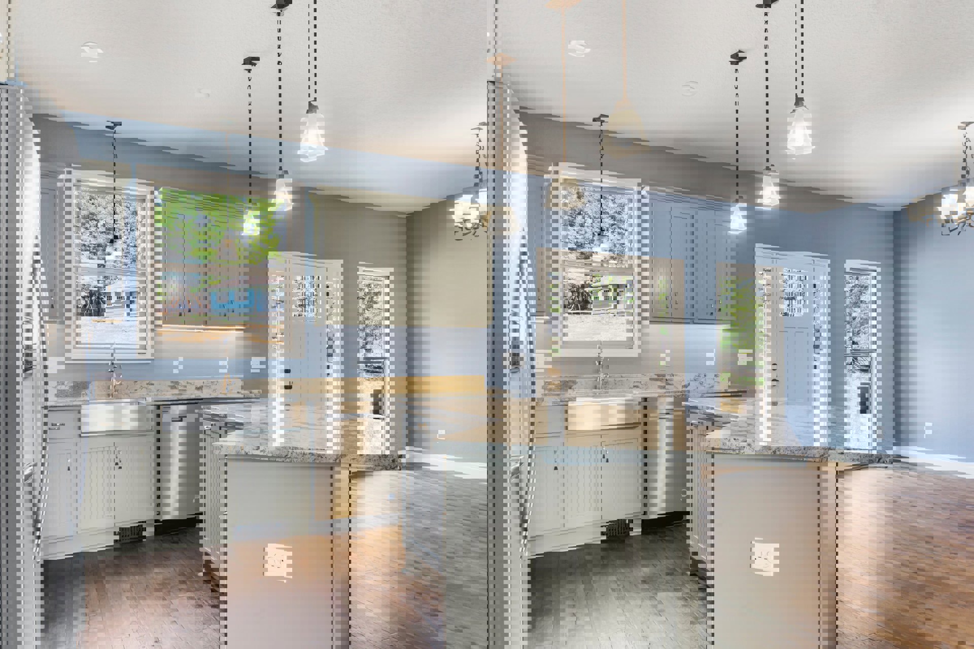 Marble kitchen island with waterfall edge, stainless steel refrigerator and oven, white cabinetry, large window with natural light, light wood flooring, modern sink and faucet