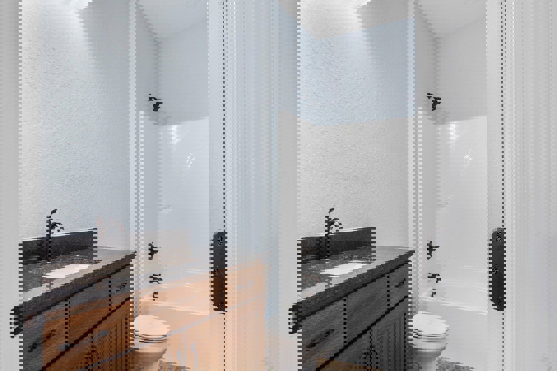 Modern bathroom featuring a white porcelain sink with chrome faucet, matching white toilet, light gray tile flooring, and a wooden vanity with stone countertop