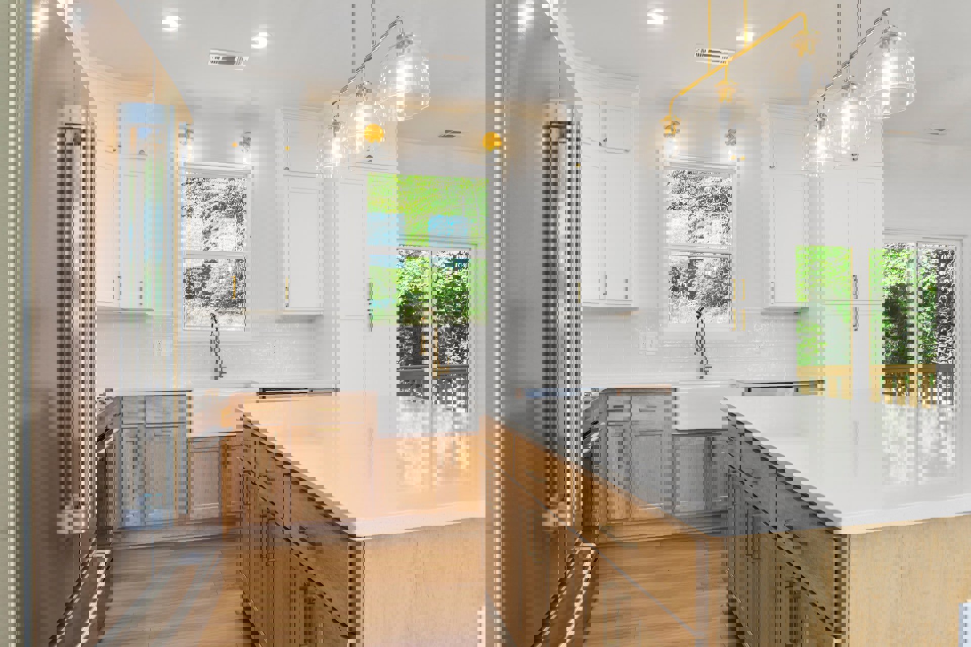 White kitchen cabinets and wooden countertops, wood flooring, window overlooking trees, clear glass light fixture, metal bar detail near sink.