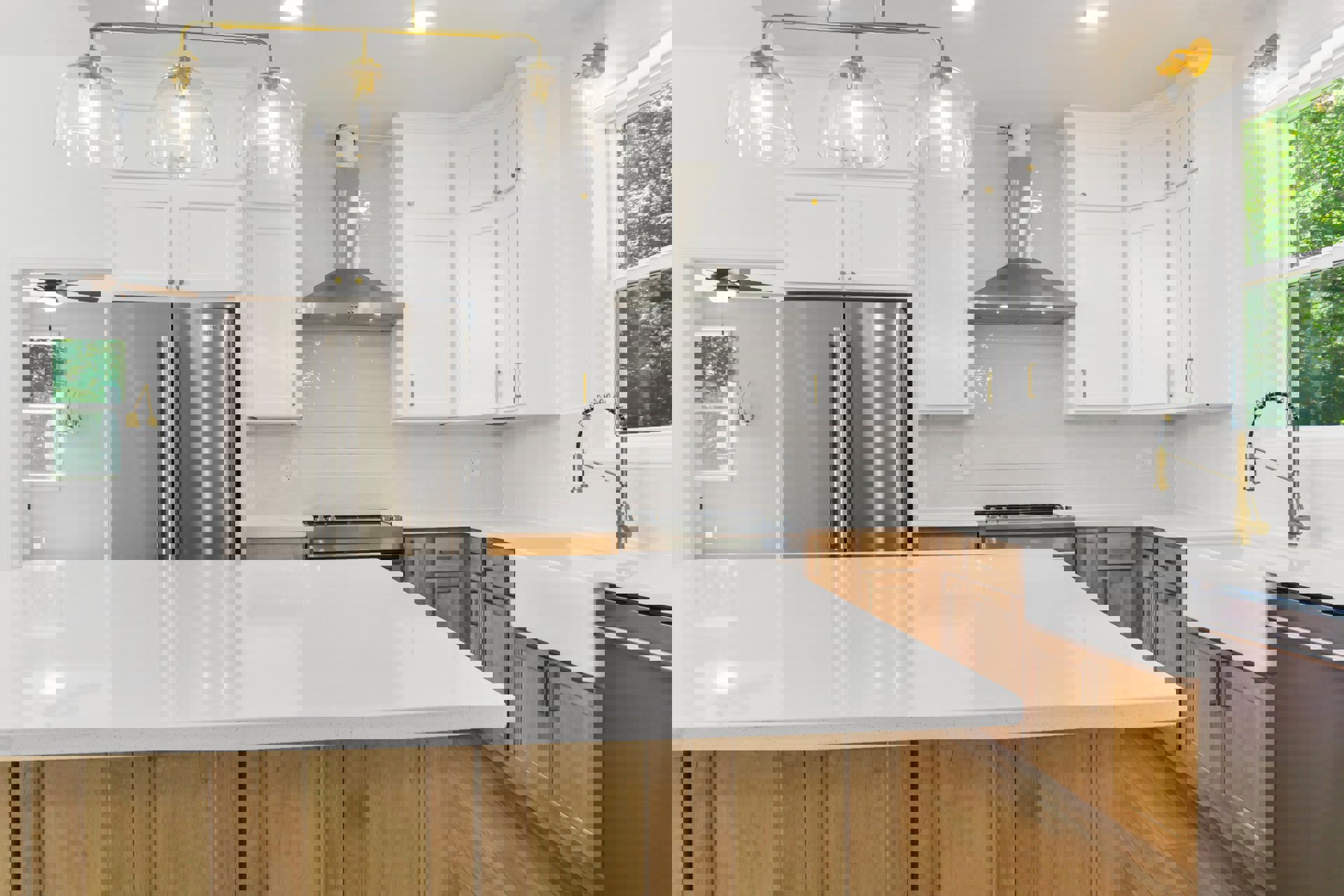 White kitchen cabinets, stainless steel double-door refrigerator, white countertop, gold faucet with black hose, clear glass dome light fixture, grey wall in background