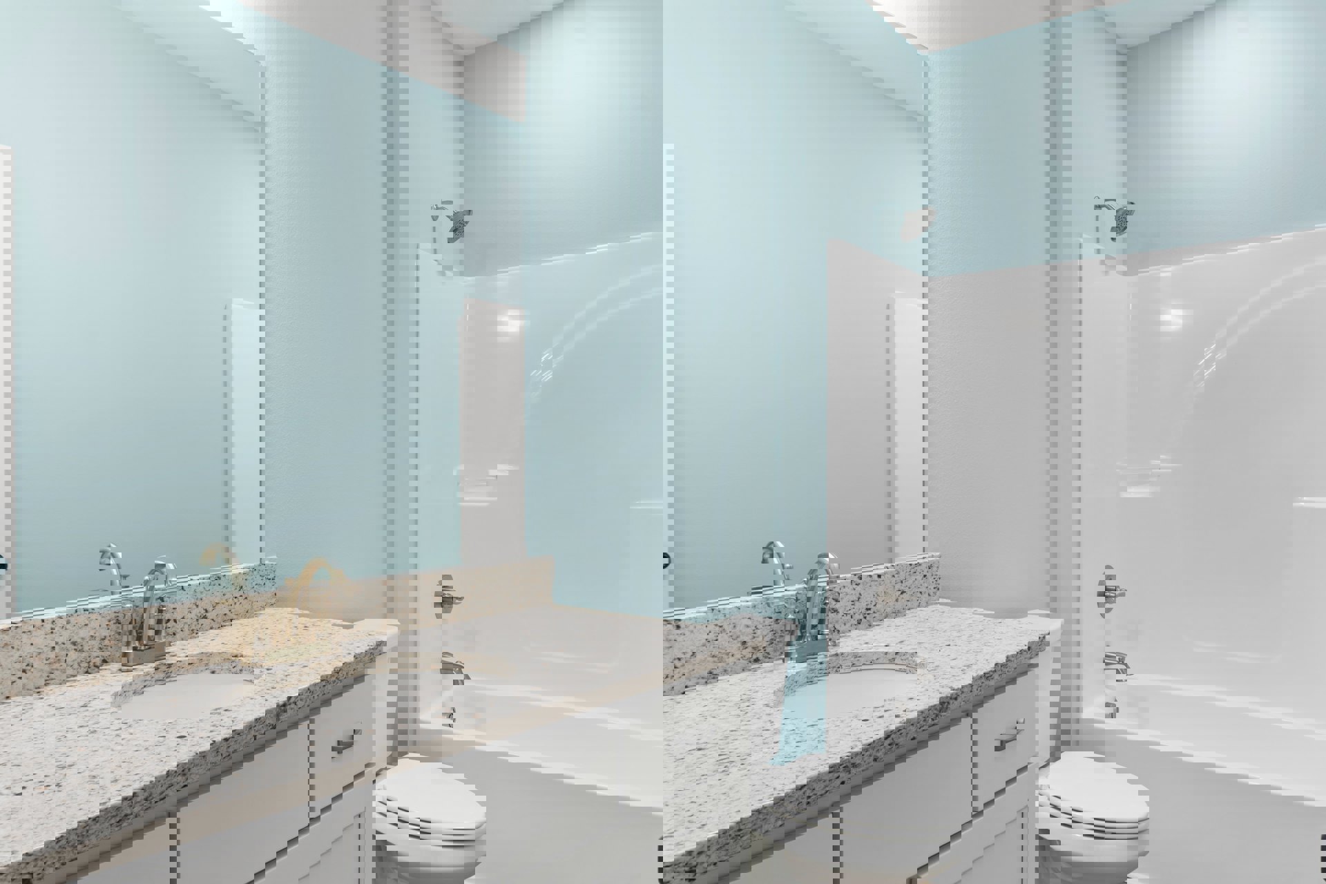 Bathroom with white bathtub, toilet, and sink; silver faucet and knob; blue painted wall; white door; tile flooring; wall-mounted mirror.