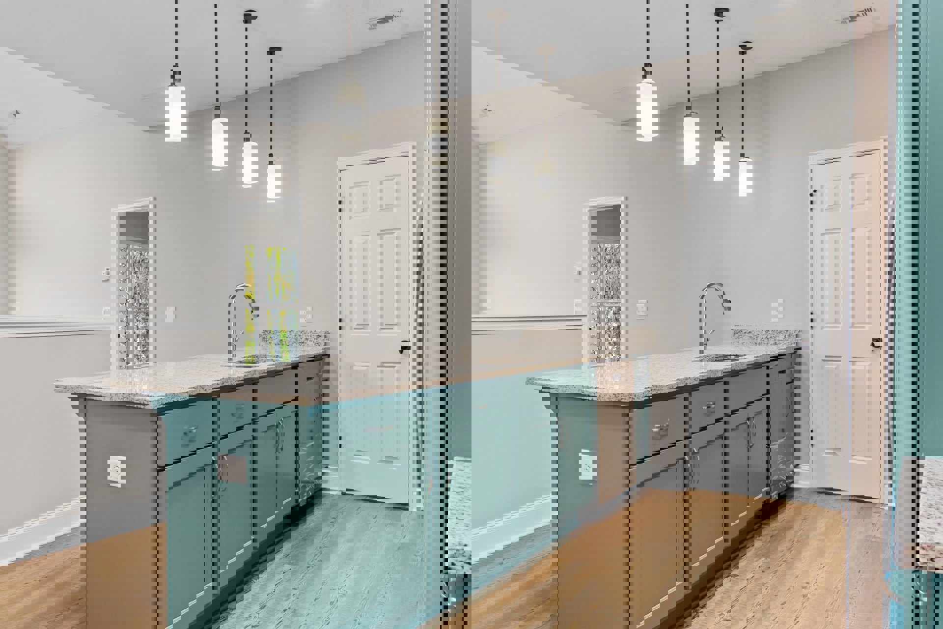 Blue kitchen island with white cabinetry, black hardware, tile backsplash, stainless steel sink and faucet, white door with black knob, window showing trees outside, light fixture