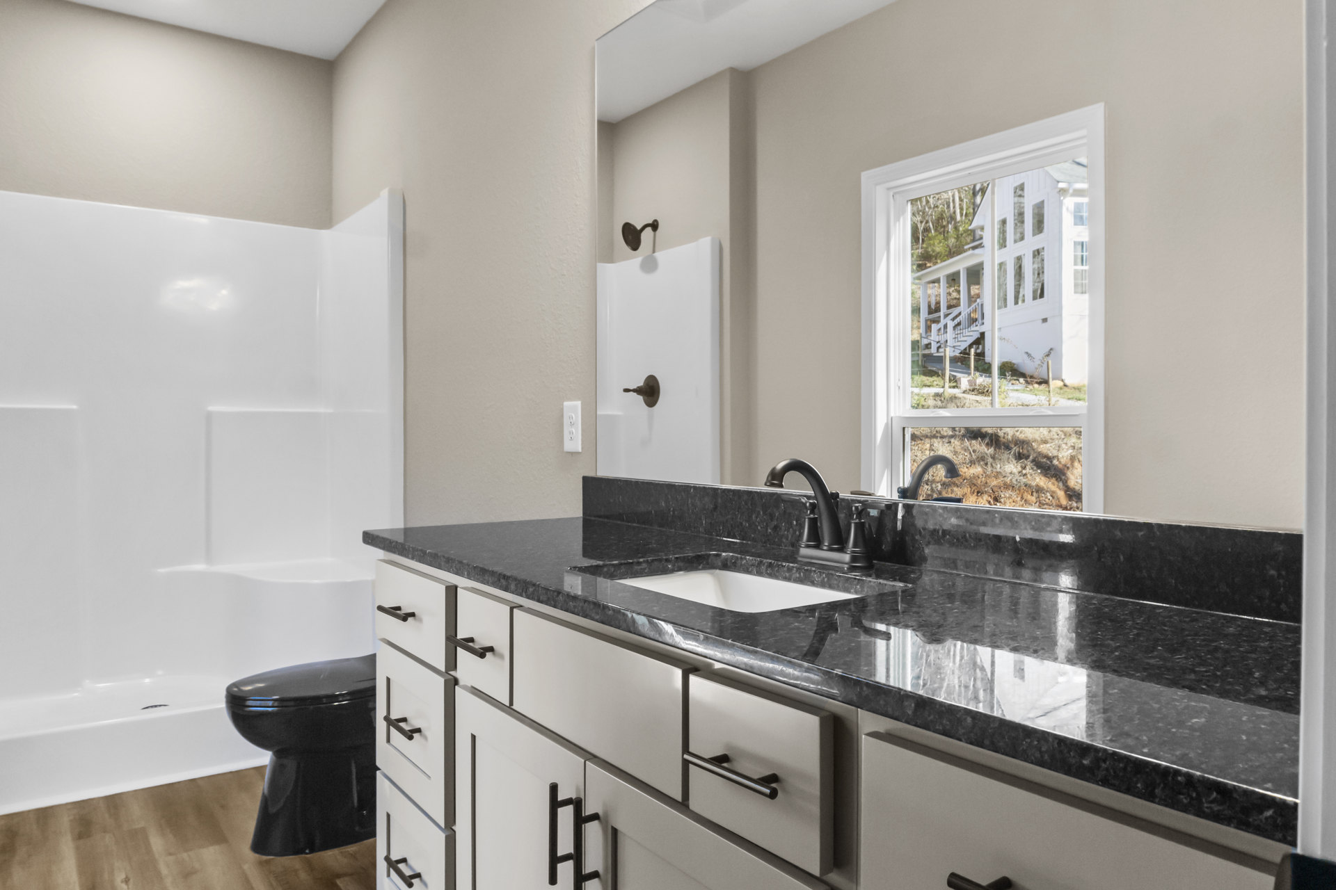 Bathroom featuring black granite countertop, white walls, black toilet, tile flooring, and modern plumbing fixtures