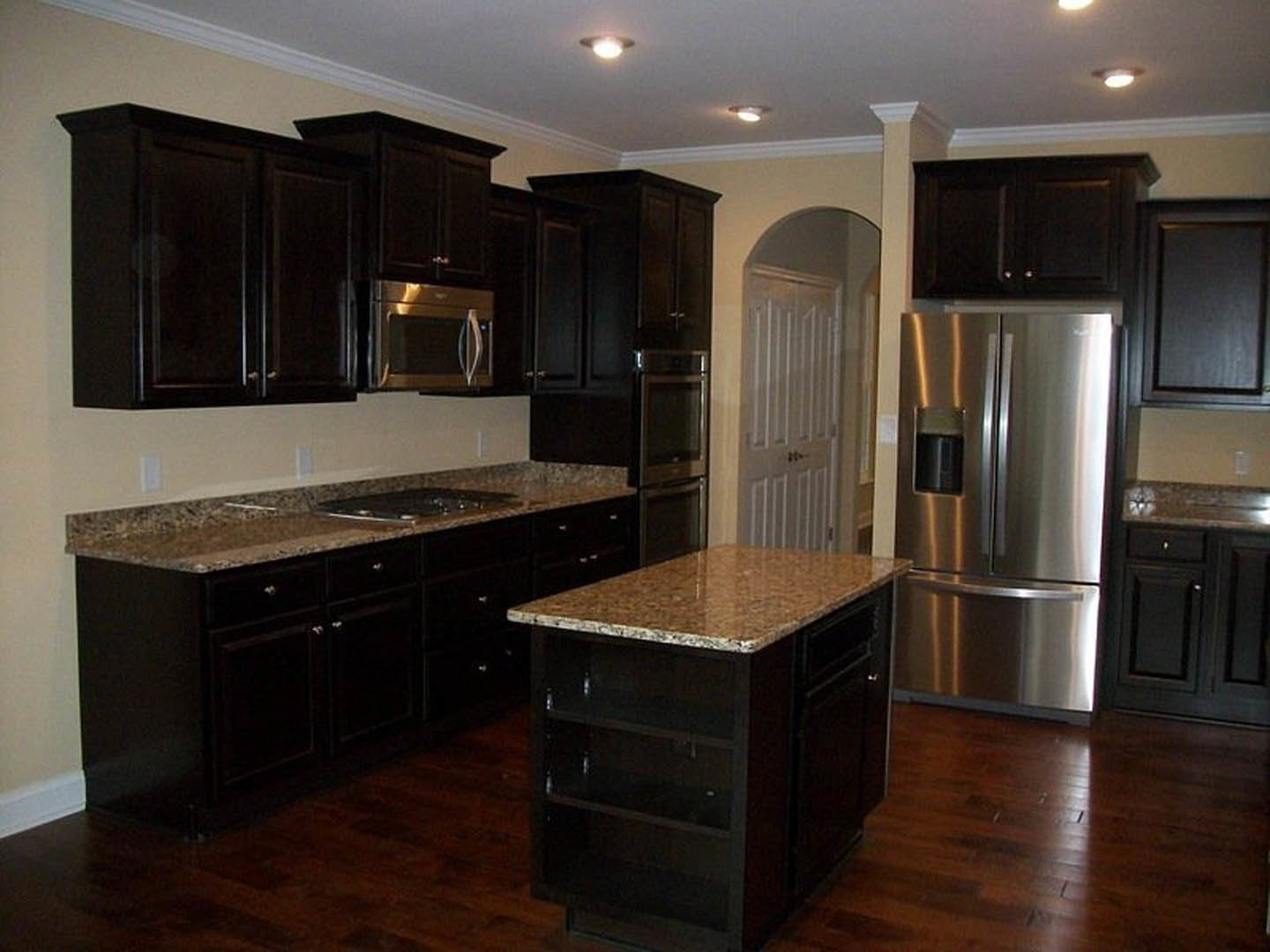 Kitchen with dark wood cabinets, granite countertops, stainless steel appliances, and a central island with marble top