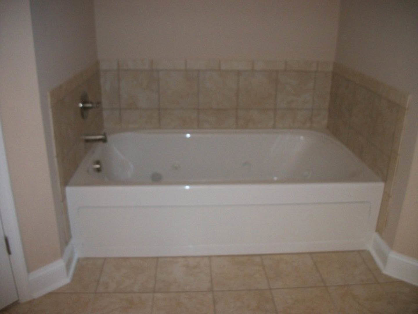 White freestanding bathtub with chrome faucet, surrounded by marble tile floor and wall in modern bathroom