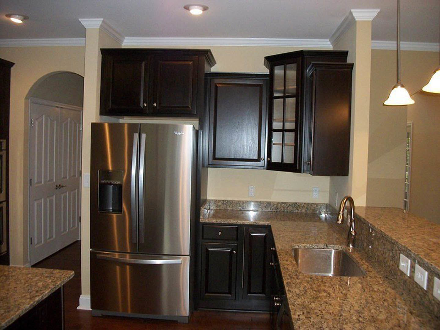 Kitchen with stainless steel refrigerator, granite countertops, white cabinetry, and light-colored walls