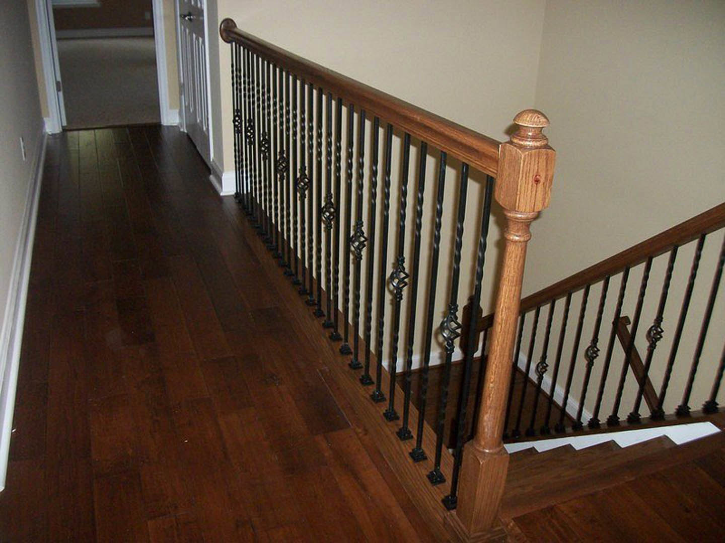 Wood staircase with black metal railings, hardwood flooring, and white walls in a residential interior