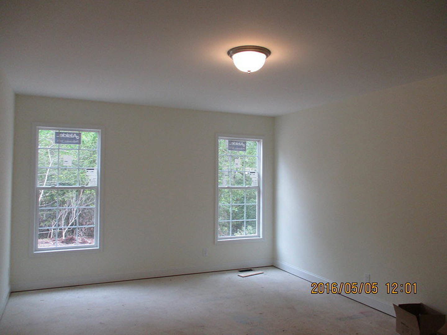 Bright room with white-framed windows, plaster walls, light fixture on ceiling, hardwood flooring, and window blinds