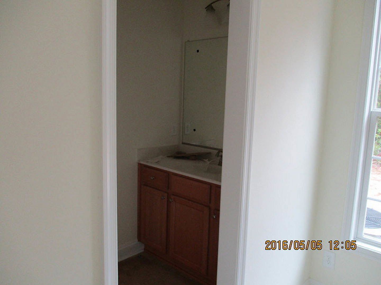 Bathroom with white tile walls, modern sink, wood cabinetry, chrome faucet, and visible electrical outlet.