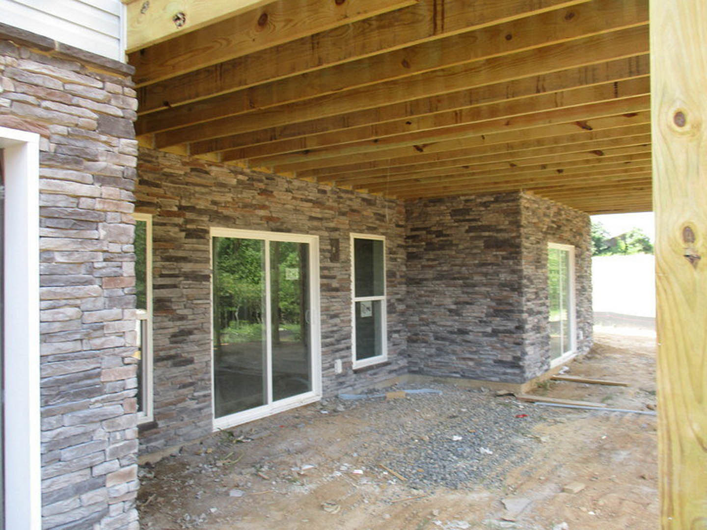 Wood-framed roof and exposed brick walls, glass door and window with white frames, dirt floor, white rectangular object with black border