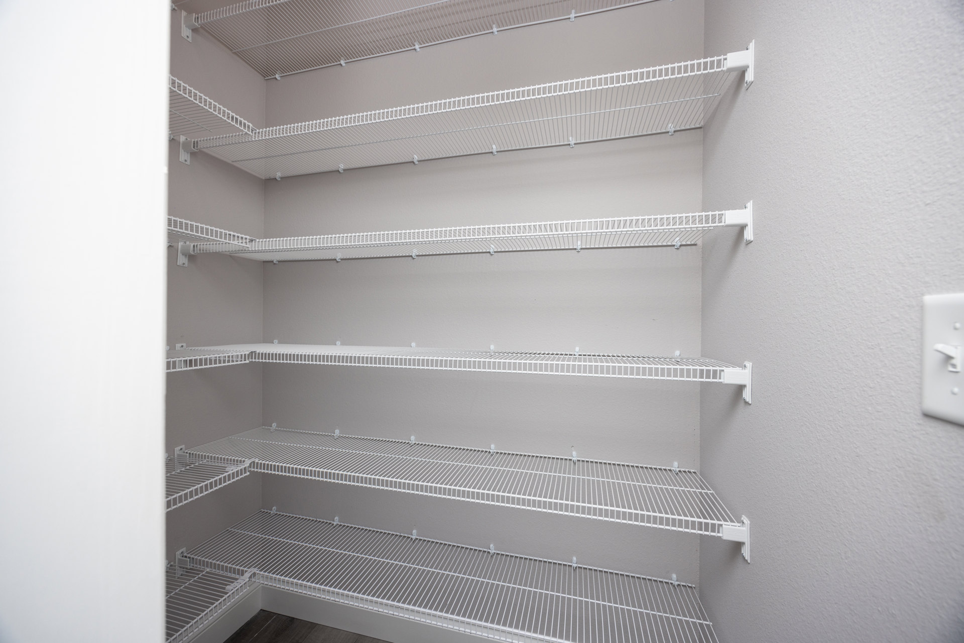 White wire shelving with pegs mounted on a wall in a room, blurred faucet visible in foreground.