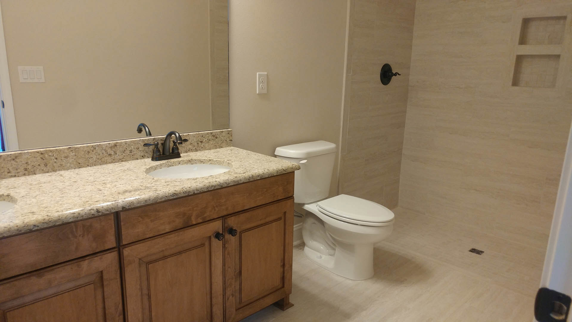 Modern bathroom with white porcelain sink and toilet, chrome faucet, light gray tile flooring, and neutral wall tiles