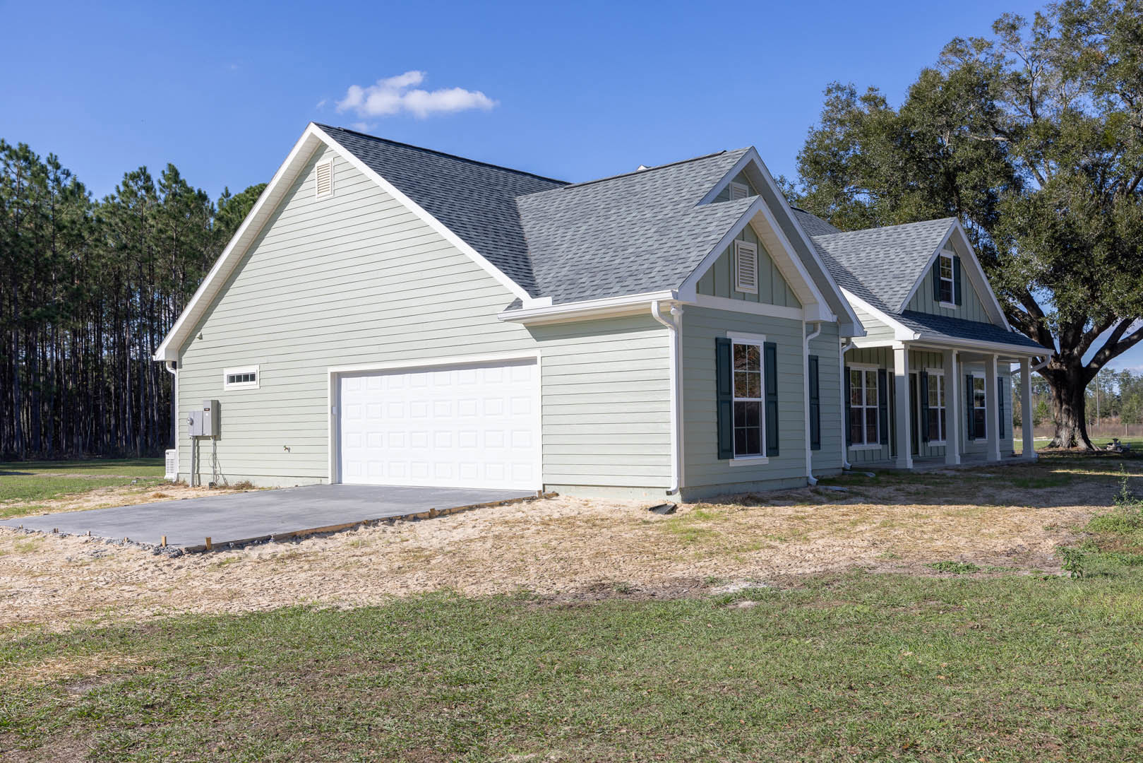 Two-story house with white siding, attached garage with white door, paved driveway, green lawn, and blue sky with scattered clouds; Robert Frost Farm visible in the background.