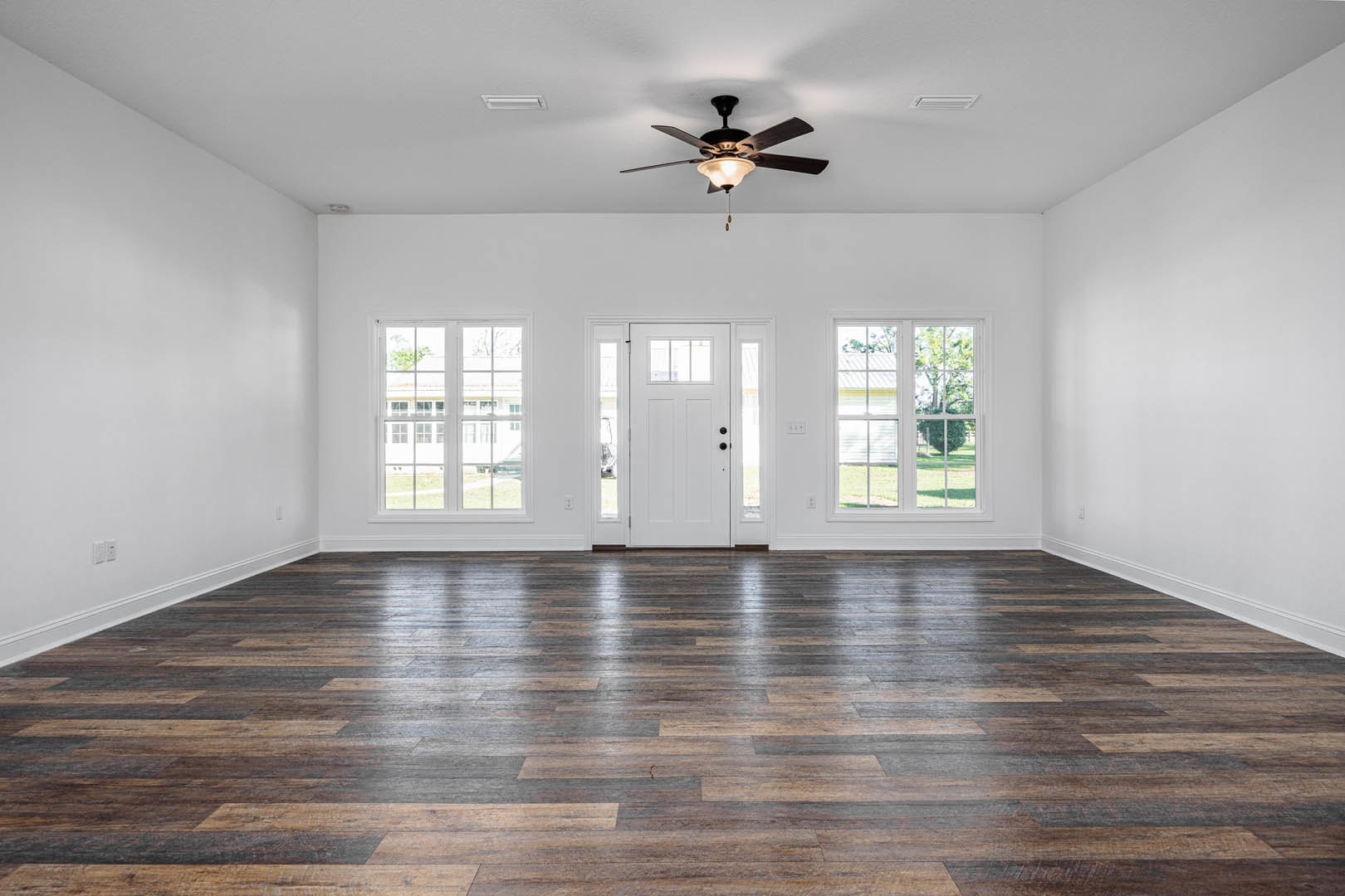 Ceiling fan with light fixture above wood laminate flooring, white door with glass panels, multi-pane window, plaster walls and ceiling