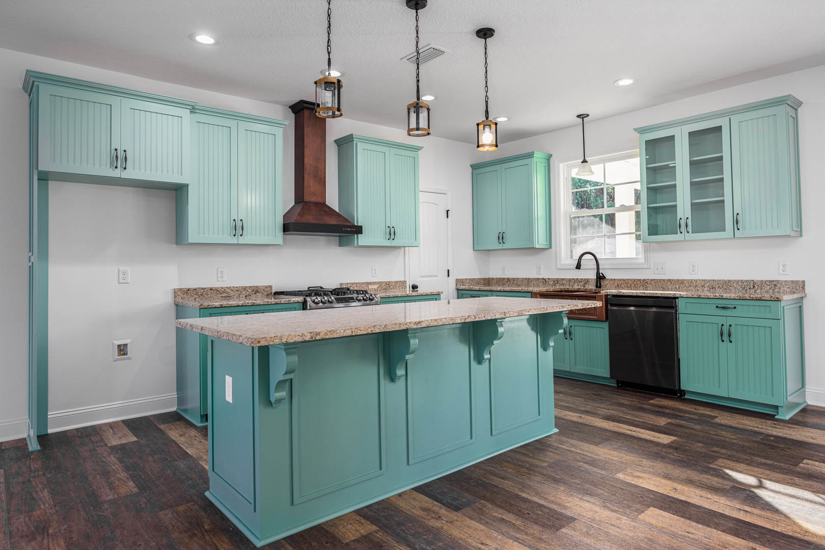 Spacious kitchen featuring a large marble island, blue cabinetry, black stove, glass-caged pendant light, stainless steel dishwasher, and close-up of cabinet drawers