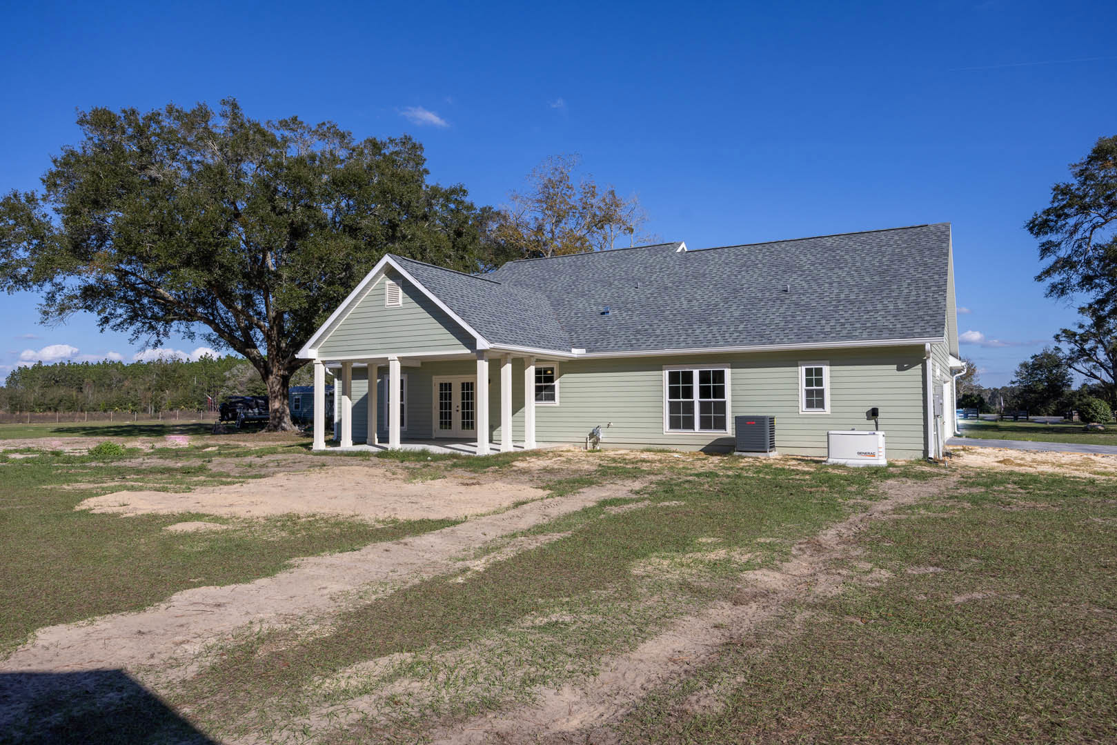 Two-story house with white roof and multi-pane windows, surrounded by a large grassy yard and mature trees, with Robert Frost Farm visible in the background.