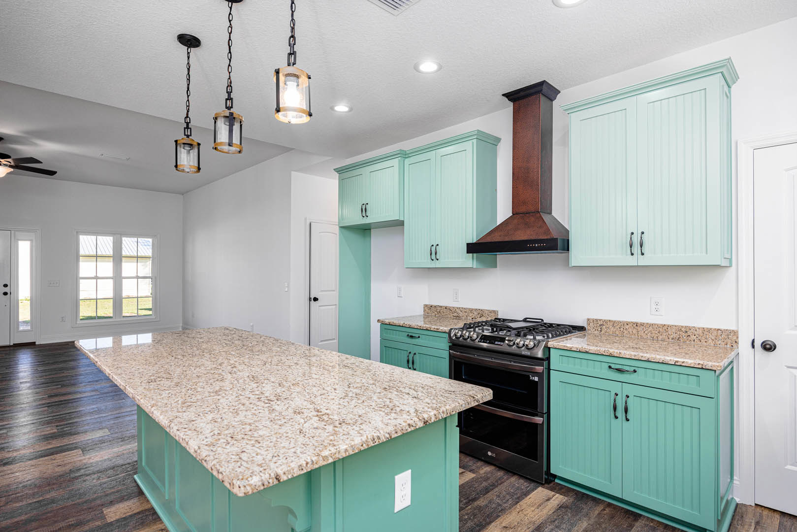 Marble countertop kitchen with stainless steel stove, white cabinetry, close-up of cabinet and drawer, white outlet, window with white frame