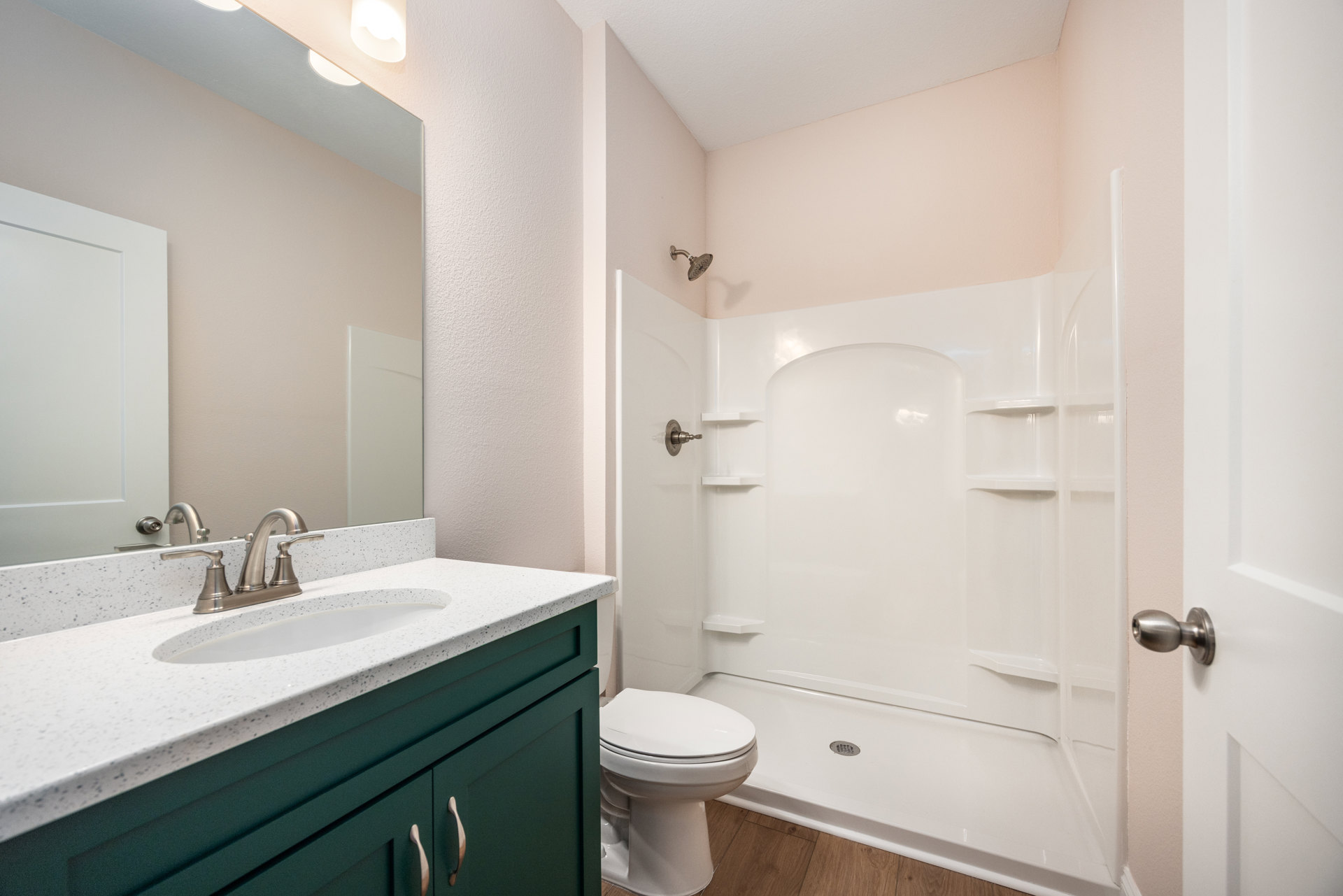 Modern bathroom with white tile walls, glass-enclosed shower, rectangular sink with silver faucet, wall-mounted mirror, and white toilet