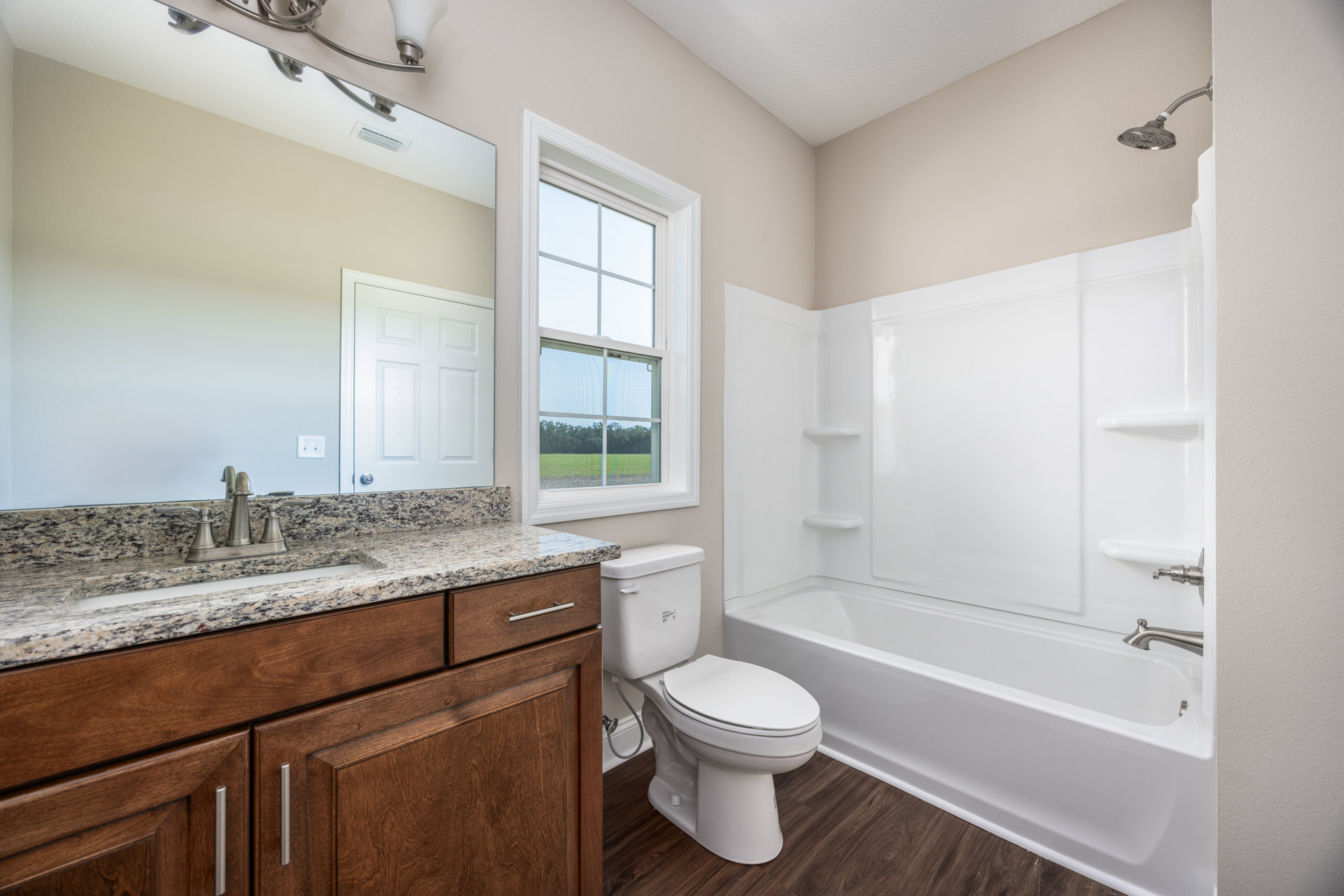 Bathroom with white tile floor, white toilet, rectangular sink set in light cabinetry, white-framed window, and white door.