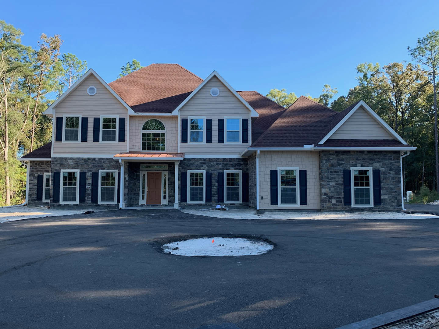 Brown-roofed house with a large circular opening at the center, surrounded by snow, white-framed windows, and a flag near the porch