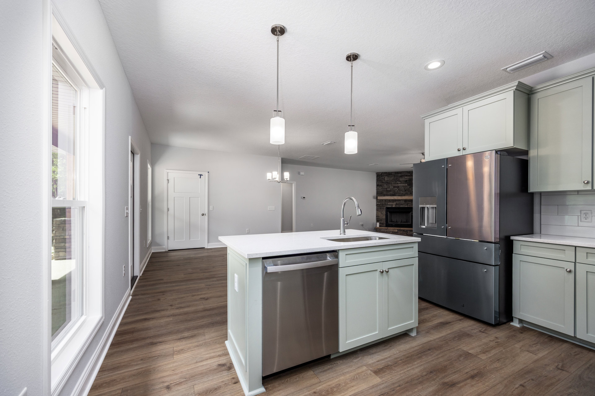 Kitchen with stainless steel refrigerator, undermount sink set in stone countertop, white cabinetry, and stainless steel dishwasher
