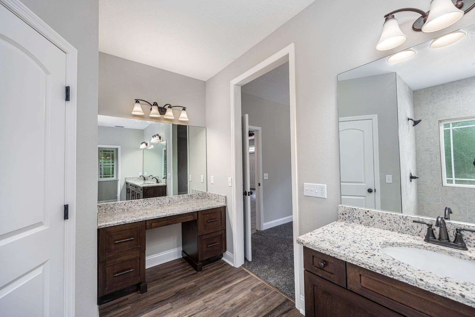 Marble countertop bathroom with rectangular mirror, three-light fixture above, green accent wall, white door, chrome faucet, and cabinetry drawers.
