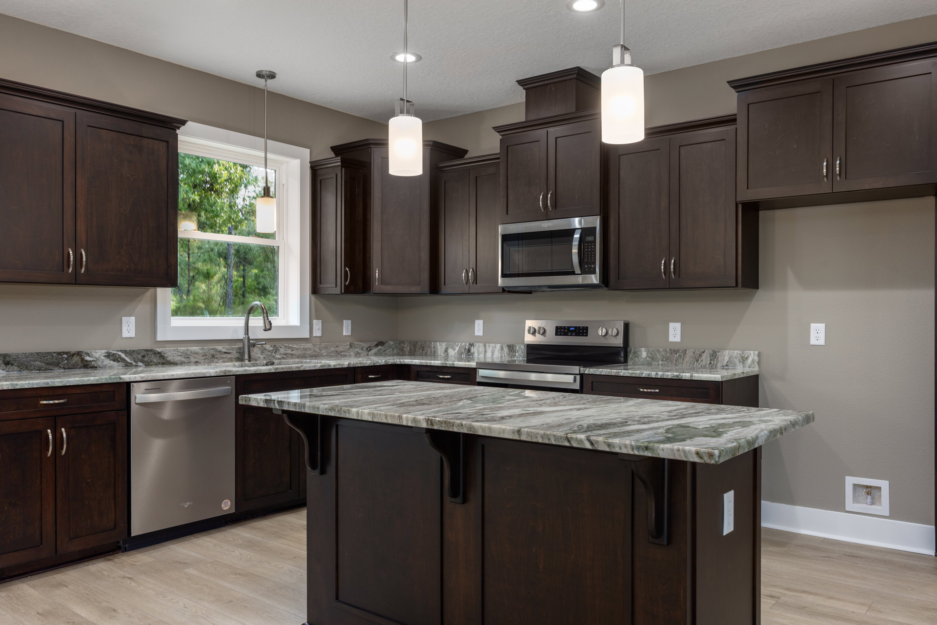 Kitchen featuring dark wood cabinets, polished granite countertops, stainless steel microwave and dishwasher, under-cabinet lighting, and a deep undermount sink.