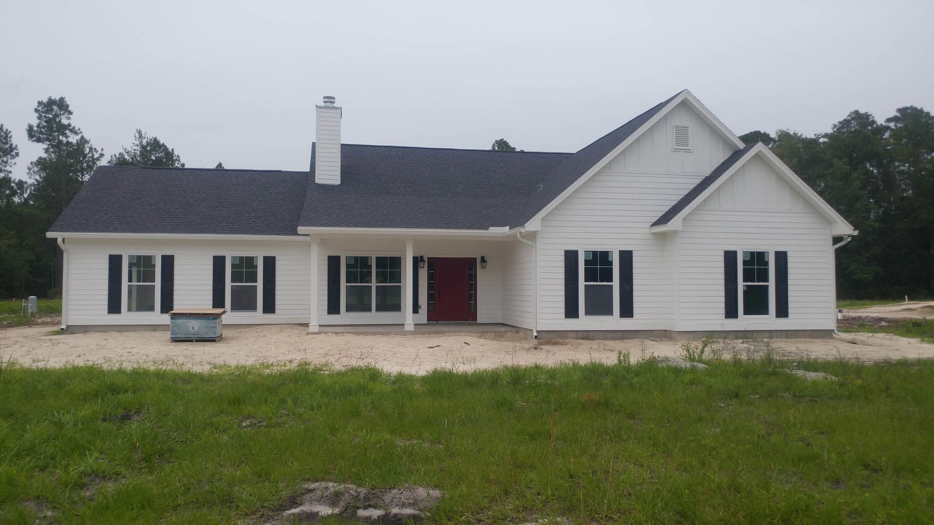 White clapboard house with red door, multi-pane windows, and manicured lawn; Robert Frost Farm visible in background.