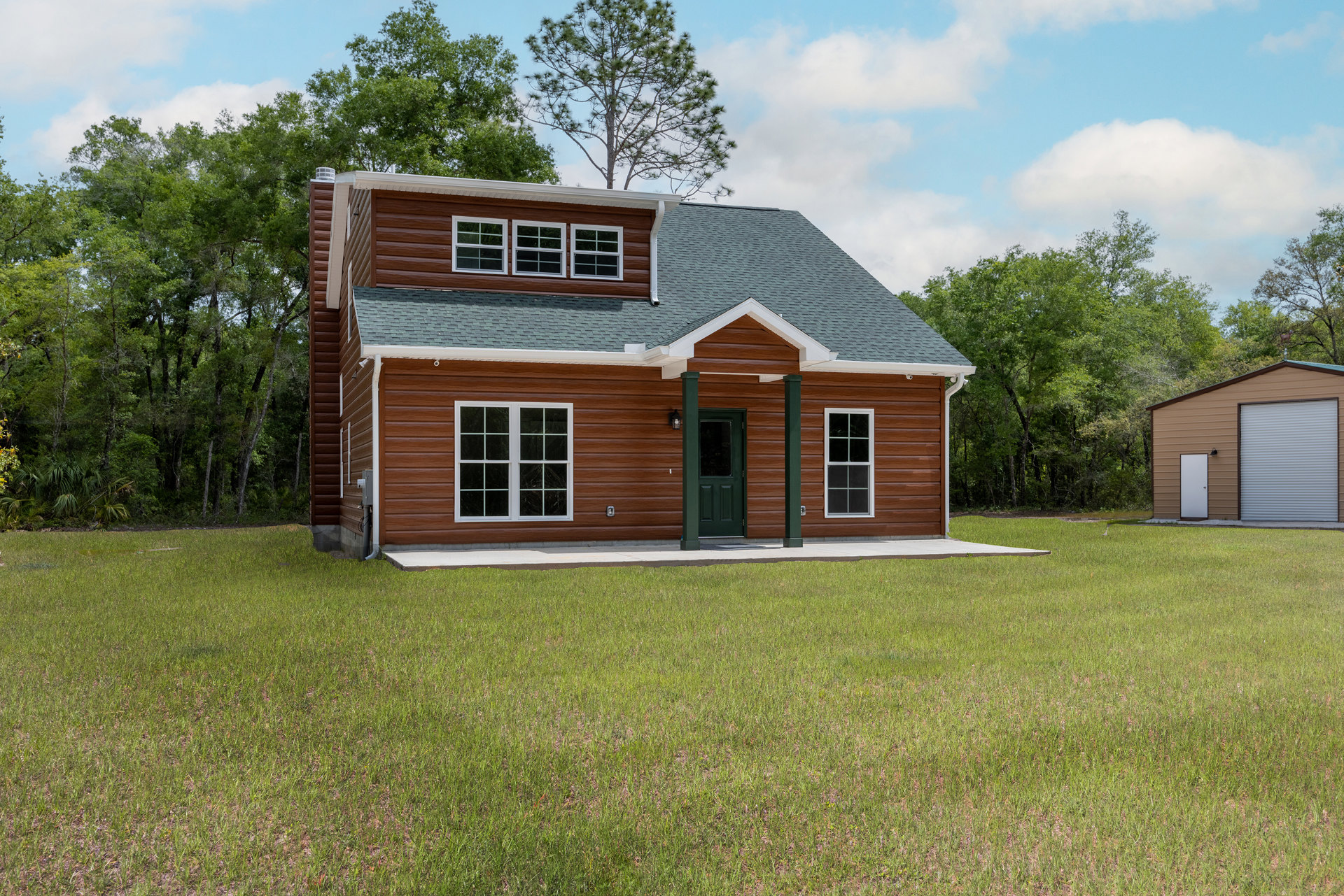 Two-story house with white siding, green front door, white-trimmed windows, and manicured green lawn