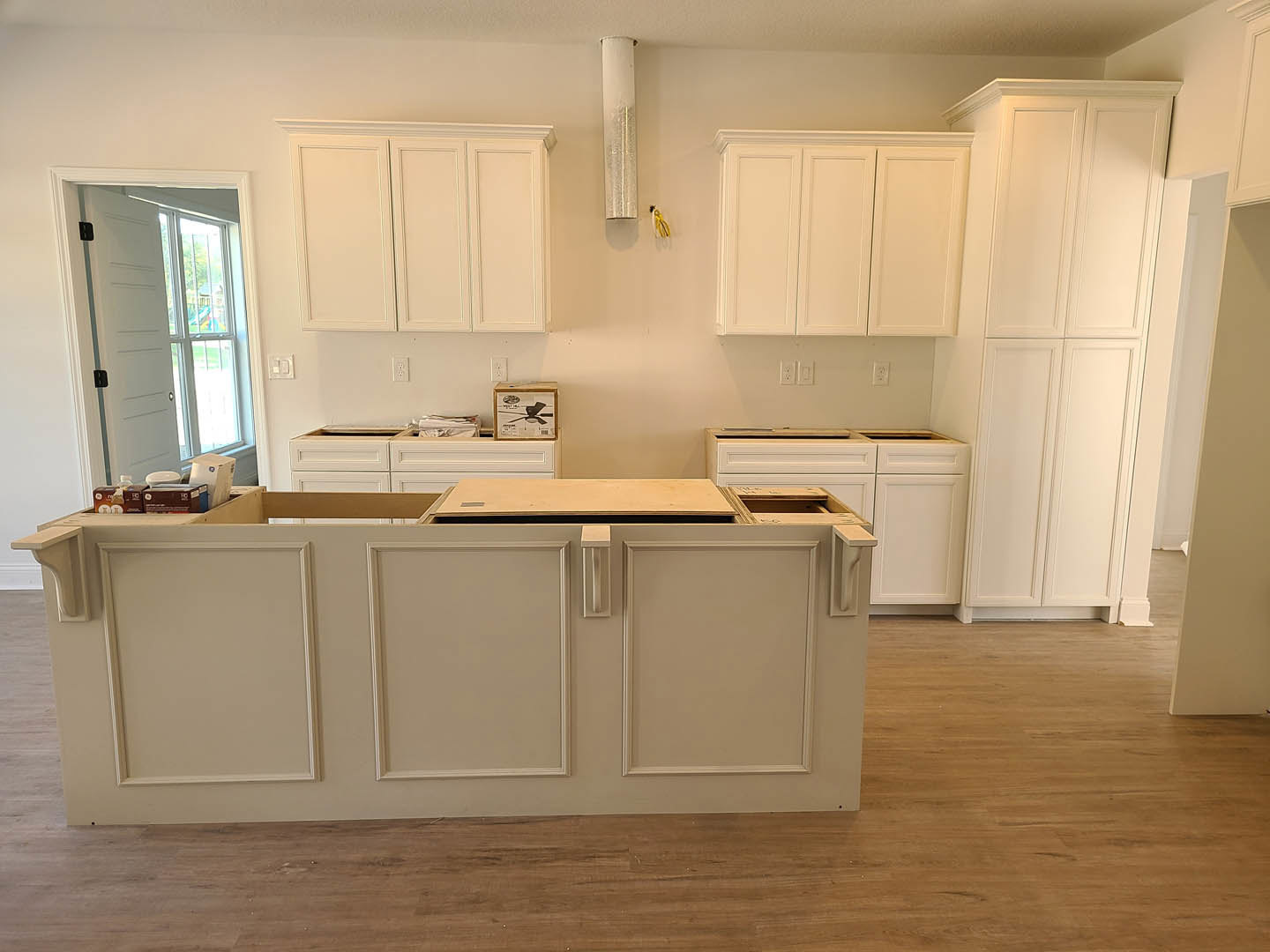 Kitchen with white shaker cabinets, wood plank flooring, quartz countertops, stainless steel sink, and black hardware