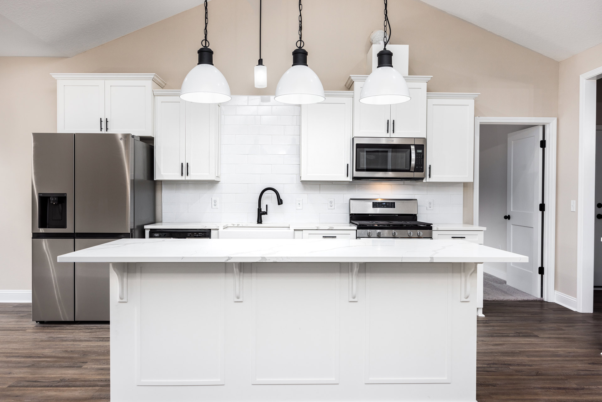White kitchen featuring white cabinets and countertops, stainless steel refrigerator, built-in microwave, stove, black faucet, and white tile backsplash