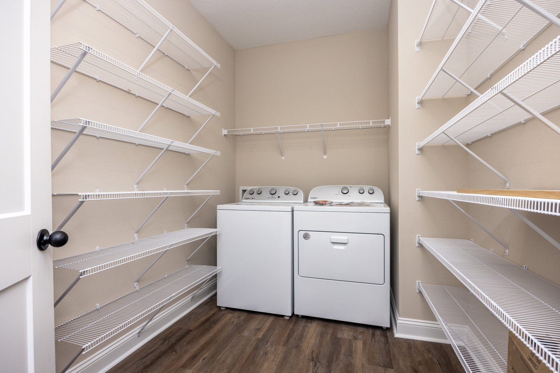 Laundry room with white washer and dryer, open wall shelves, white cabinetry, and light plaster walls