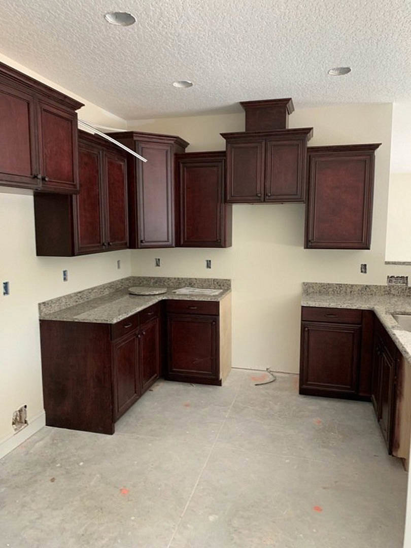 Kitchen featuring dark wood cabinetry, granite countertops, stainless steel sink, tile flooring, and built-in appliances