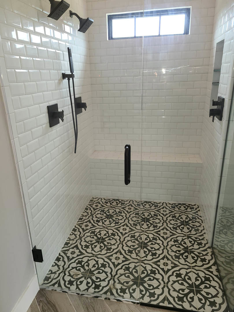 Shower with glass door, black handle, white tile walls and floor, black bathroom accessory mounted on wall, window close-up, black and white tile flooring