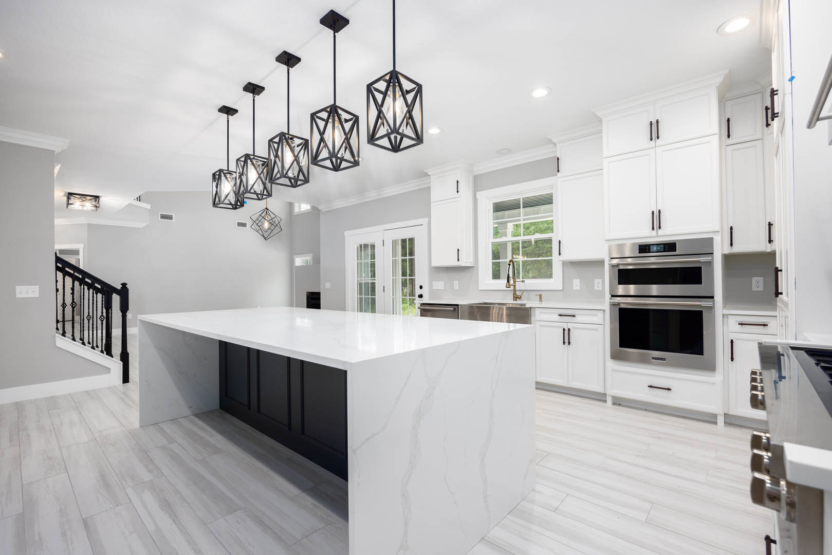 White kitchen with shaker cabinets, quartz countertop, stainless steel double oven, farmhouse sink, glass-paneled double doors, and light fixture above island