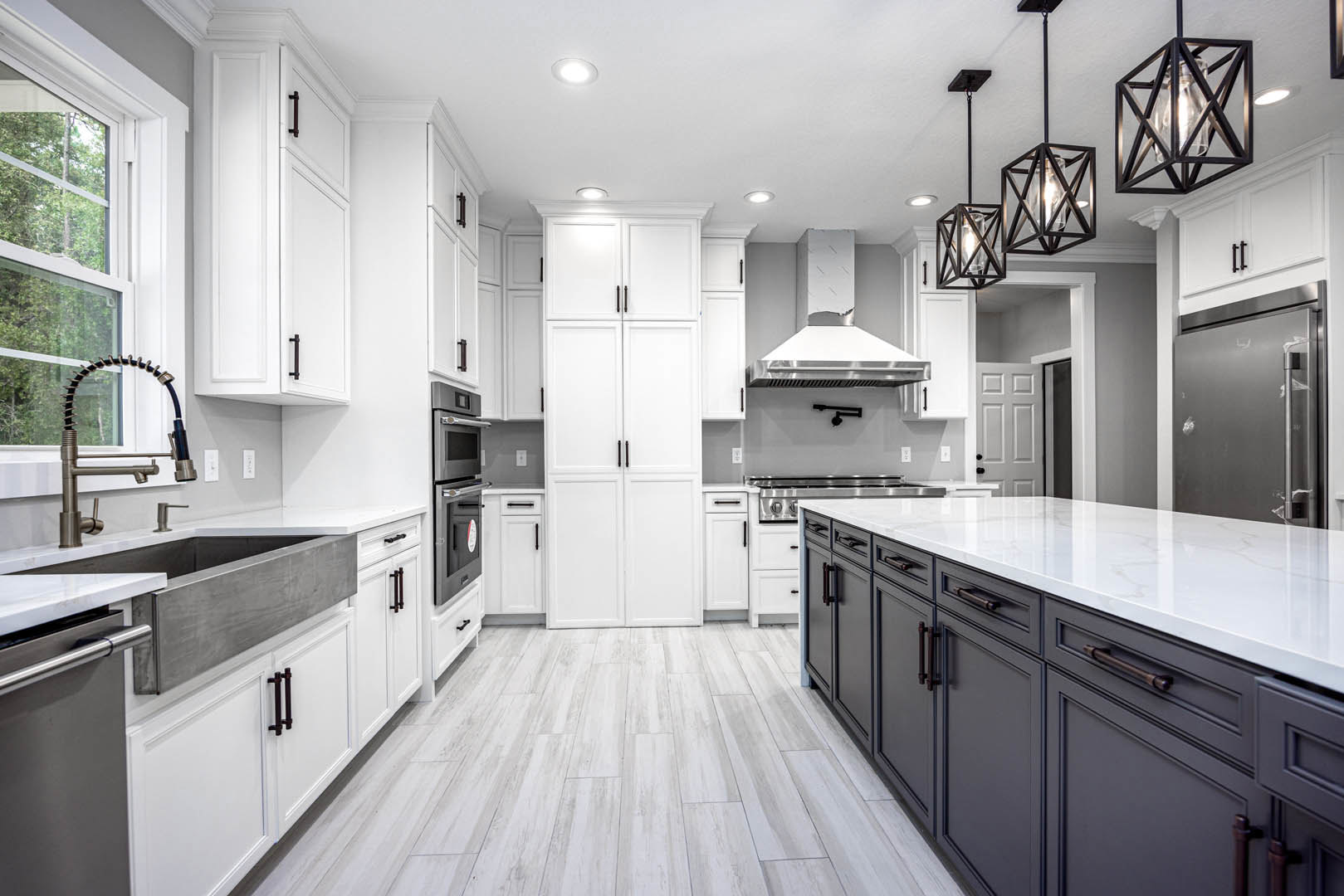 White kitchen cabinets with black handles, black refrigerator and oven, glass bulb pendant light, curved faucet over sink, light countertops and backsplash