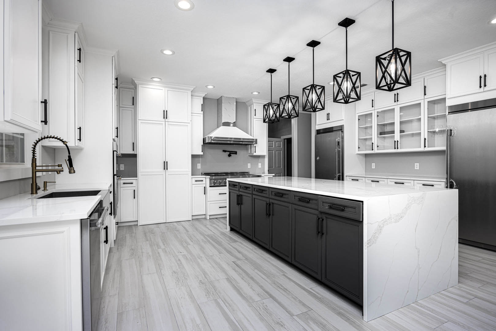 White kitchen cabinets with black appliances, black kitchen island, curved faucet, and black metal caged pendant light fixture hanging from the ceiling.