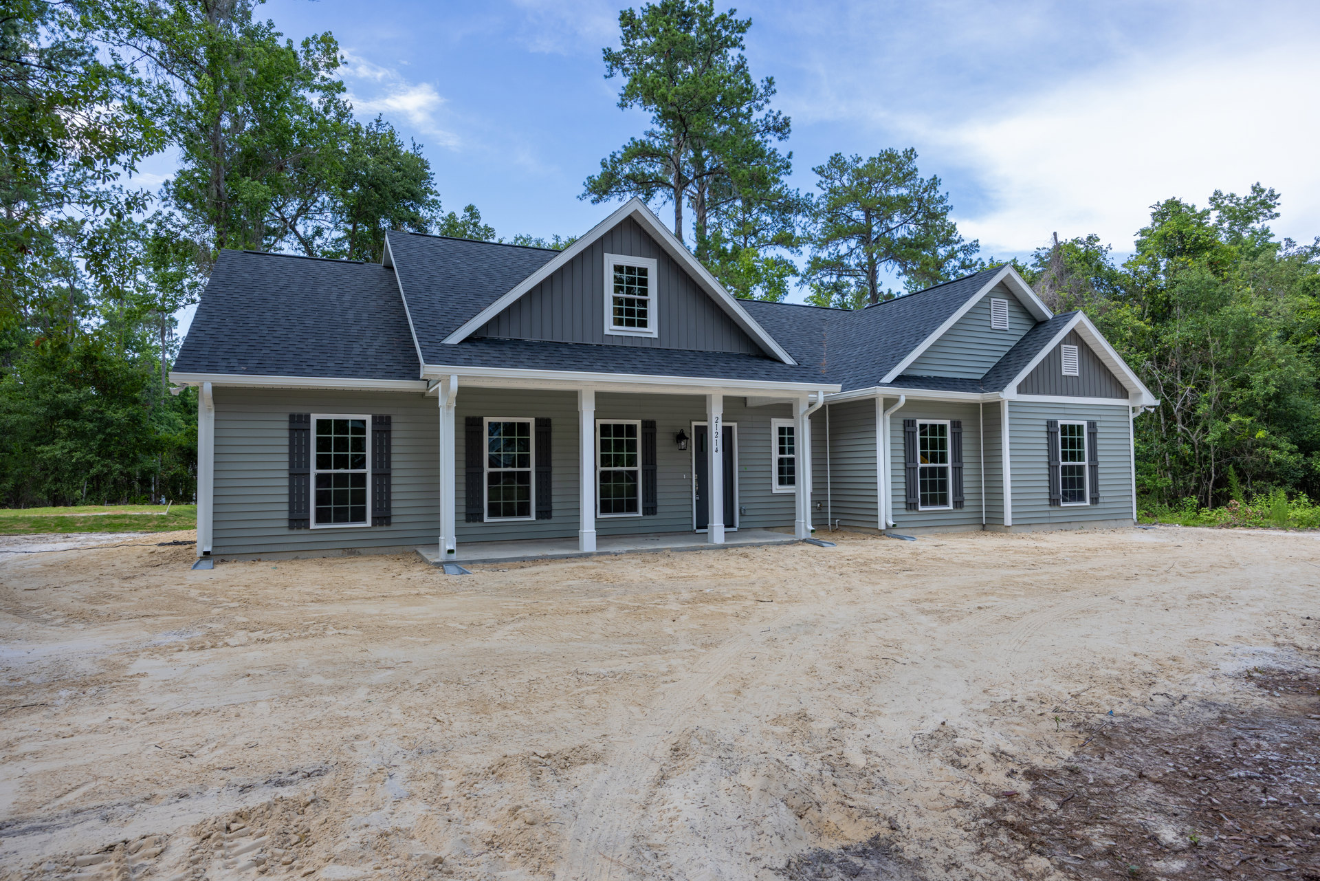 Row of houses with white trim windows and porches, dirt area in front, mature trees and Little White House visible in background under partly cloudy sky