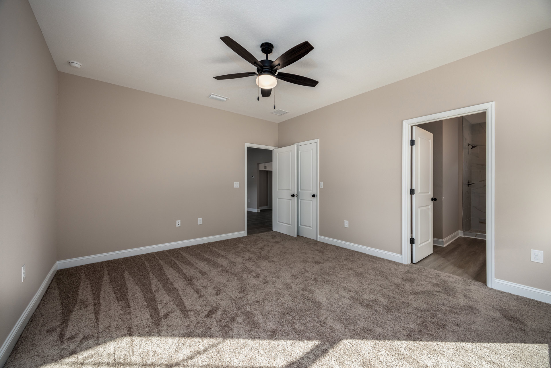 Carpeted room with white walls, ceiling fan with light fixture, open white door featuring black knob, plaster ceiling, and baseboard trim