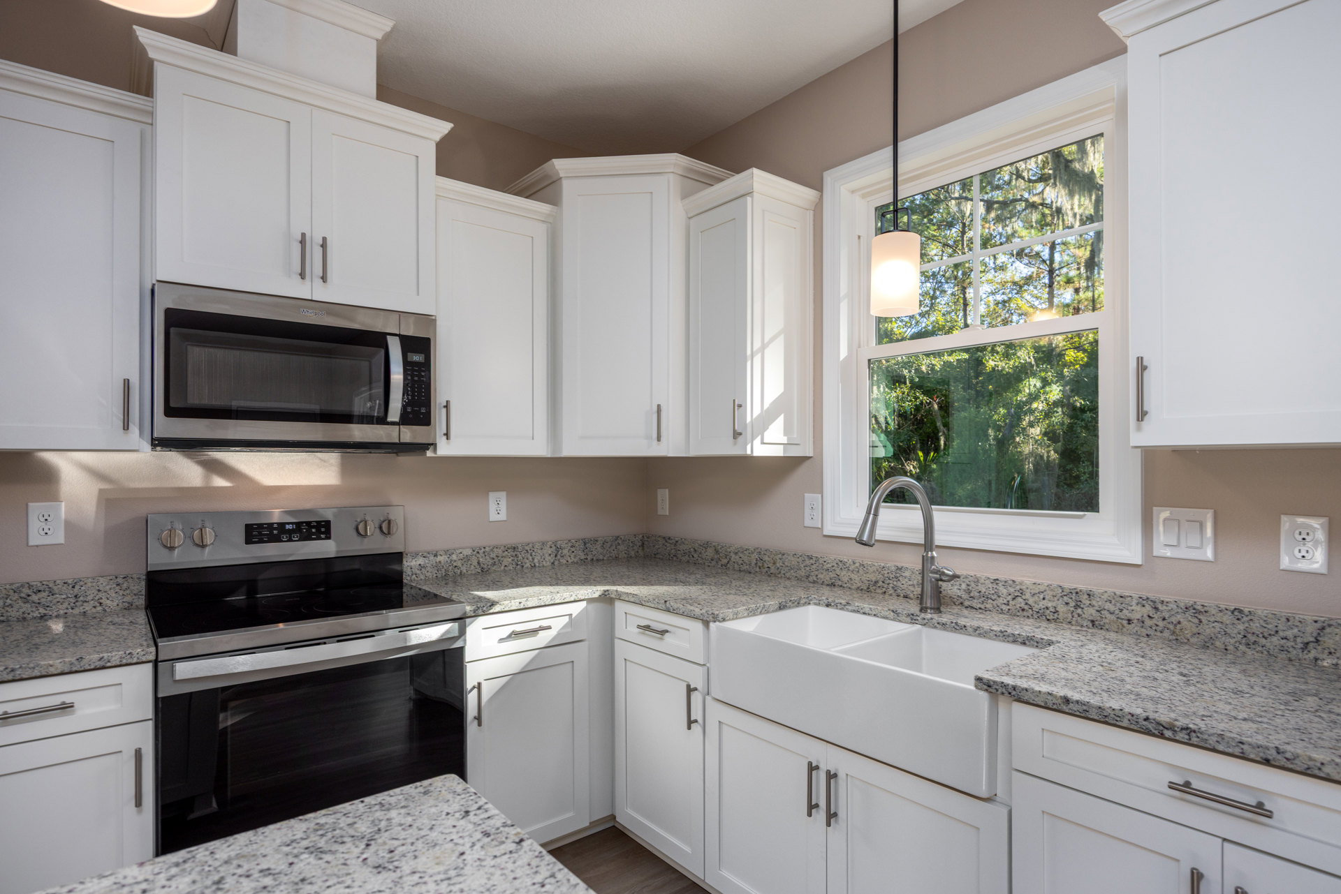 White kitchen cabinets and granite countertops, open microwave door, stove with matching countertop, close-up electrical outlet, wall sconce, ceiling light fixture