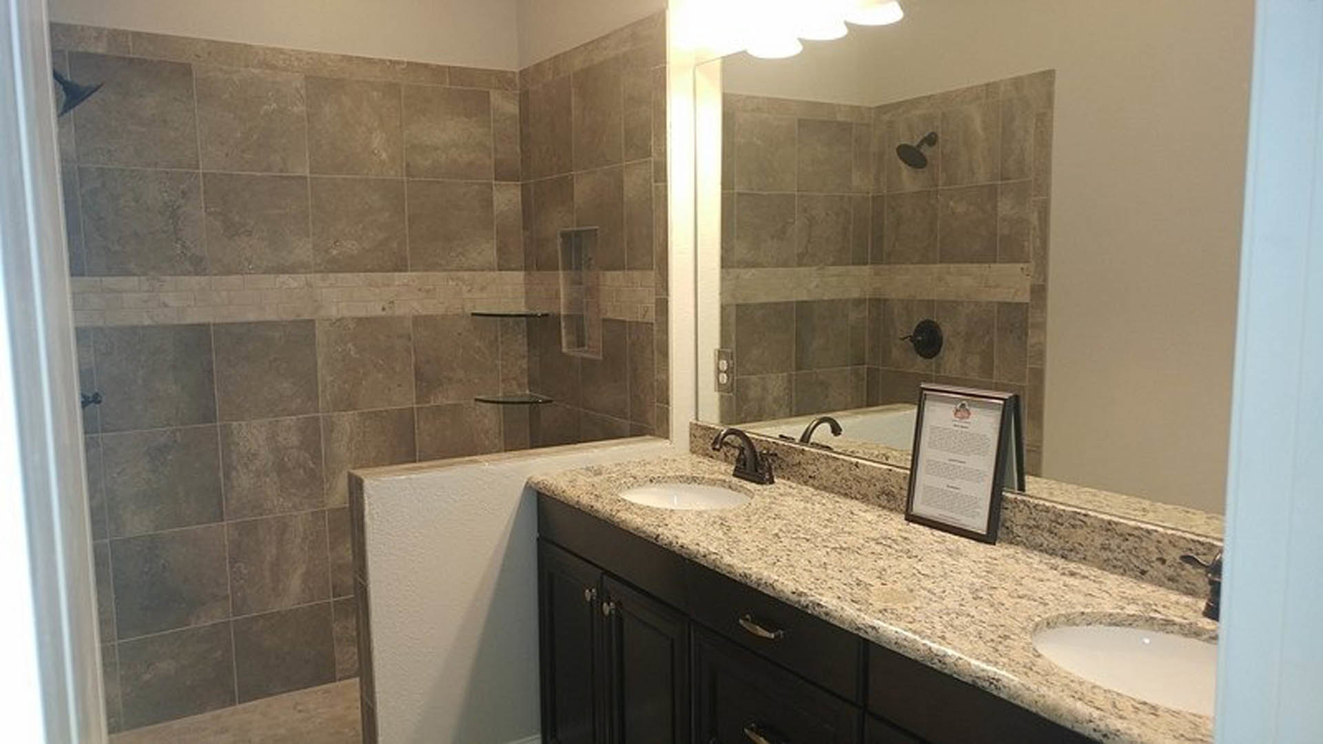 Bathroom with expansive wall mirror above wide rectangular sink, white quartz countertop, chrome faucet, light gray tile backsplash, and dark wood cabinetry